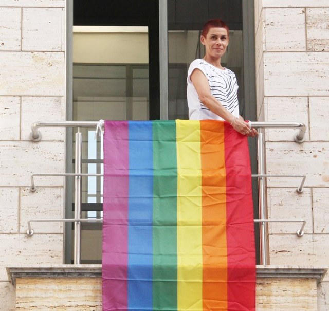 Mª Carmen Morales cuelga la bandera arcoirís para celebrar el Día Internacional del Orgullo